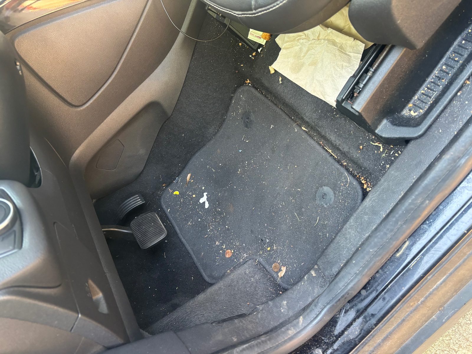 Ford Escape driver footwell before an interior detail — ground-in dirt and food debris