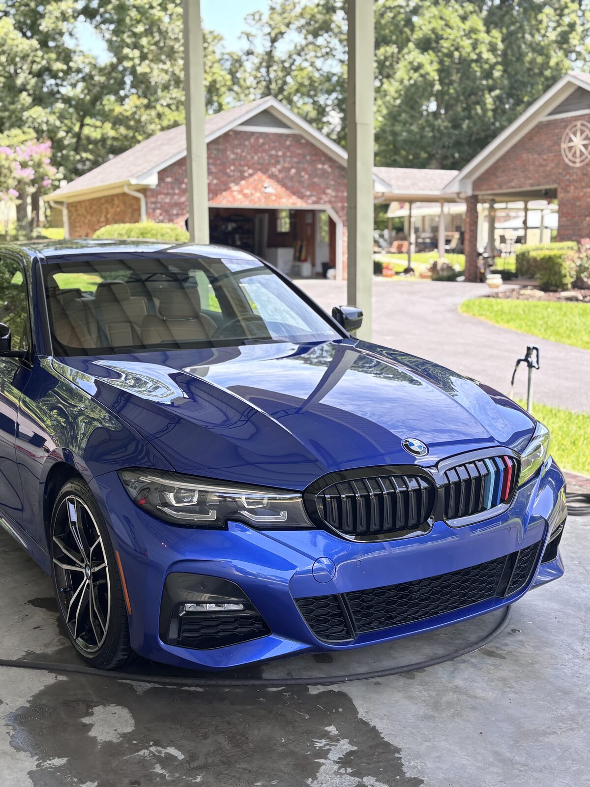 Glossy blue BMW 3 Series after full detail in the client's driveway