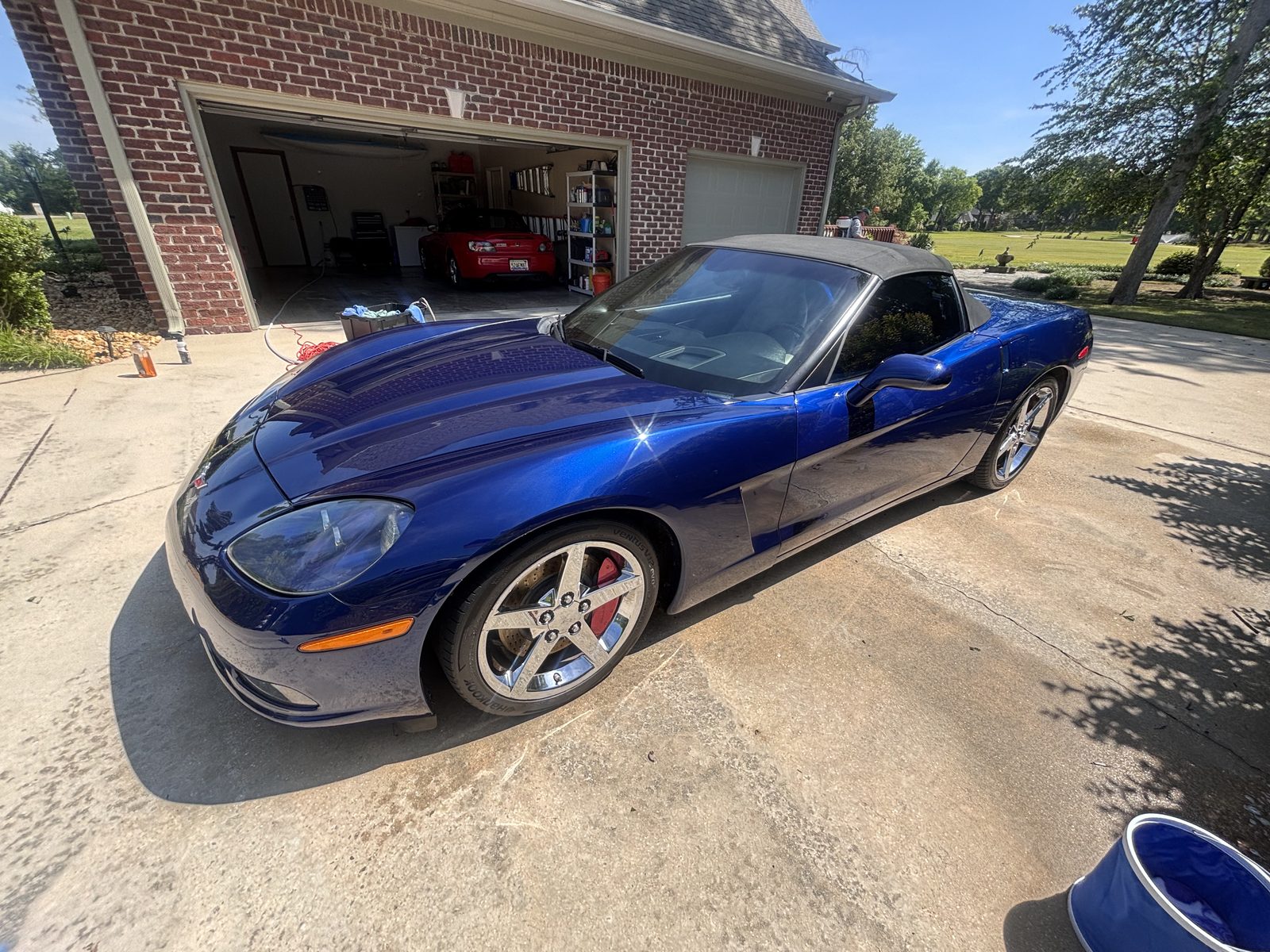 Glossy blue Corvette convertible after exterior detail in the driveway